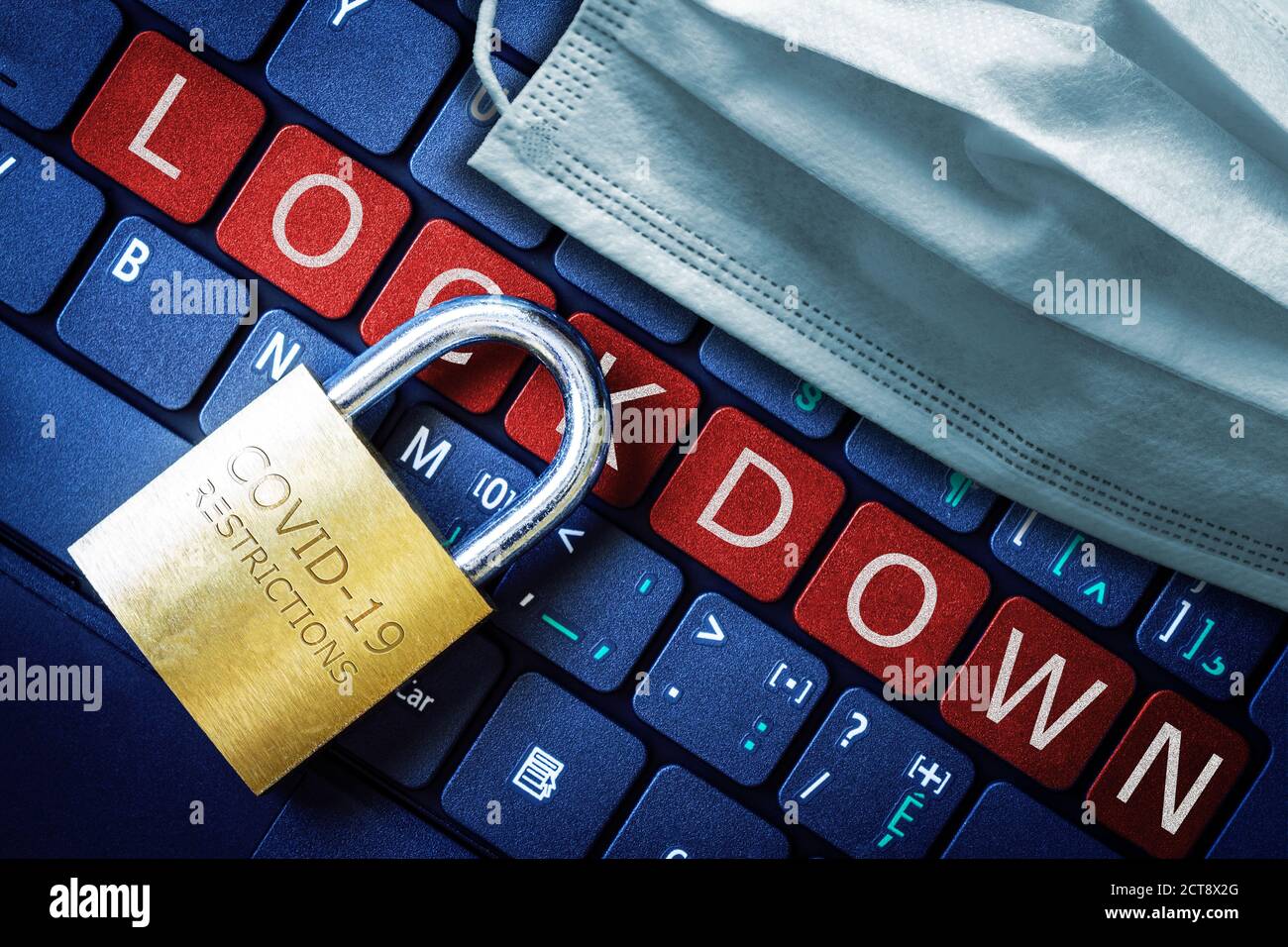 COVID-19 Coronavirus Lockdown Restriktionen Konzept illustriert durch Vorhängeschloss auf Laptop rot Alarm Tastatur Tasten und Gesichtsmaske. Stockfoto