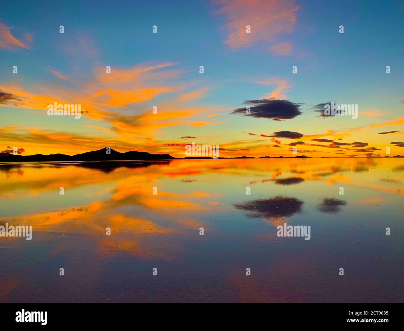 Atemberaubender orangefarbener Sonnenuntergang. Heller Sonnenuntergang Himmel. Erstaunliche Reflexion der himmlischen Wolken im Seewasser. Uyuni Salt Flats, Bolivien. Surreale Landschaft. Stockfoto