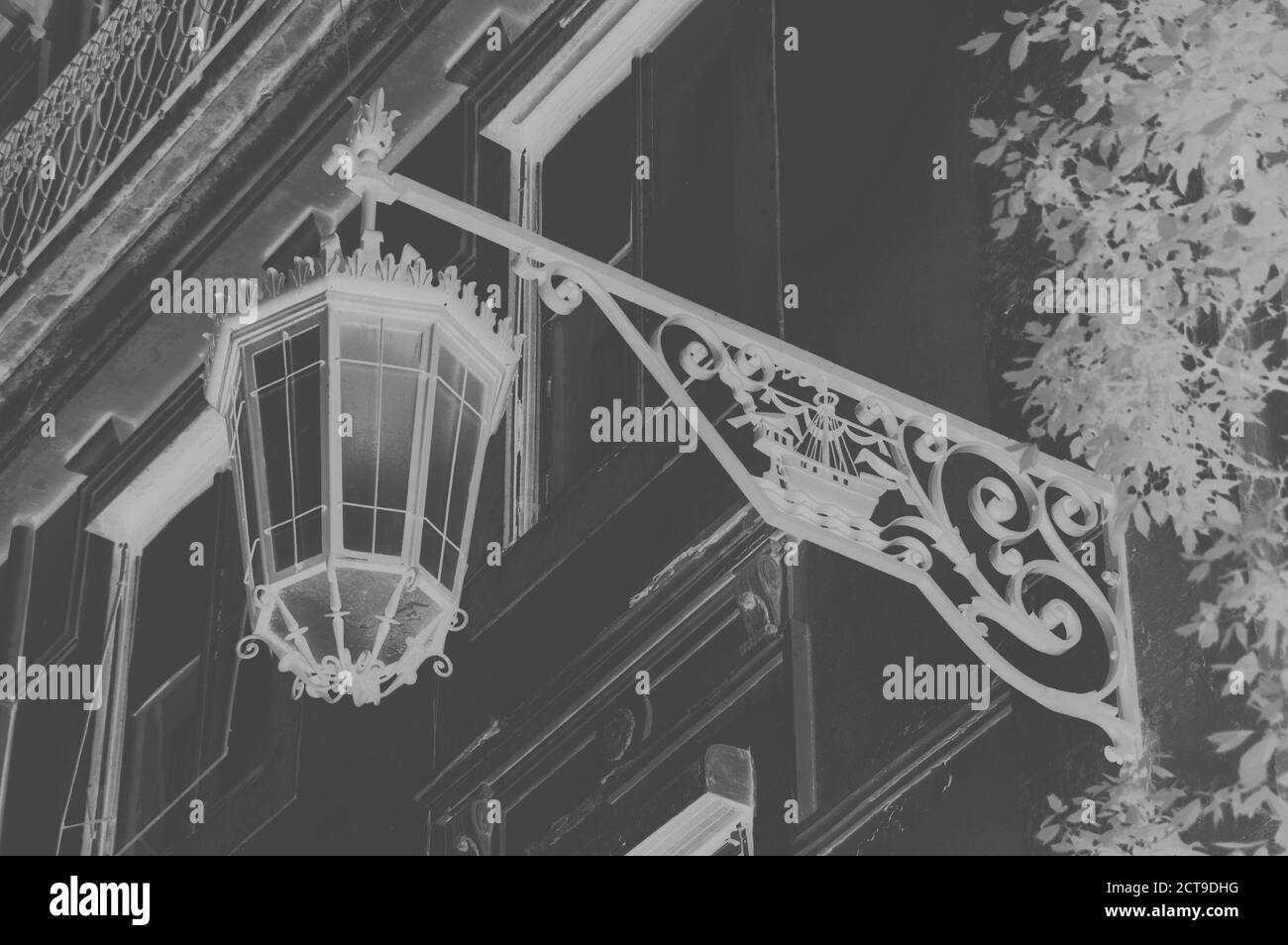 Laterne mit Lissabon-Symbol (Schiff mit zwei Raben) auf dem alten Gebäude im Zentrum von Lissabon (Portugal). Gealtertes Foto. Schwarz und Weiß. Invertierte Farben Stockfoto