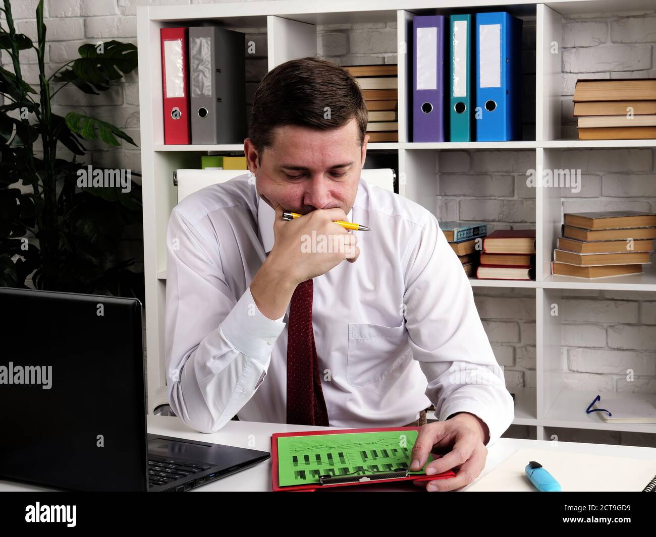 Nachdenklicher Geschäftsmann untersucht schlechte Unternehmensergebnisse. Stockfoto