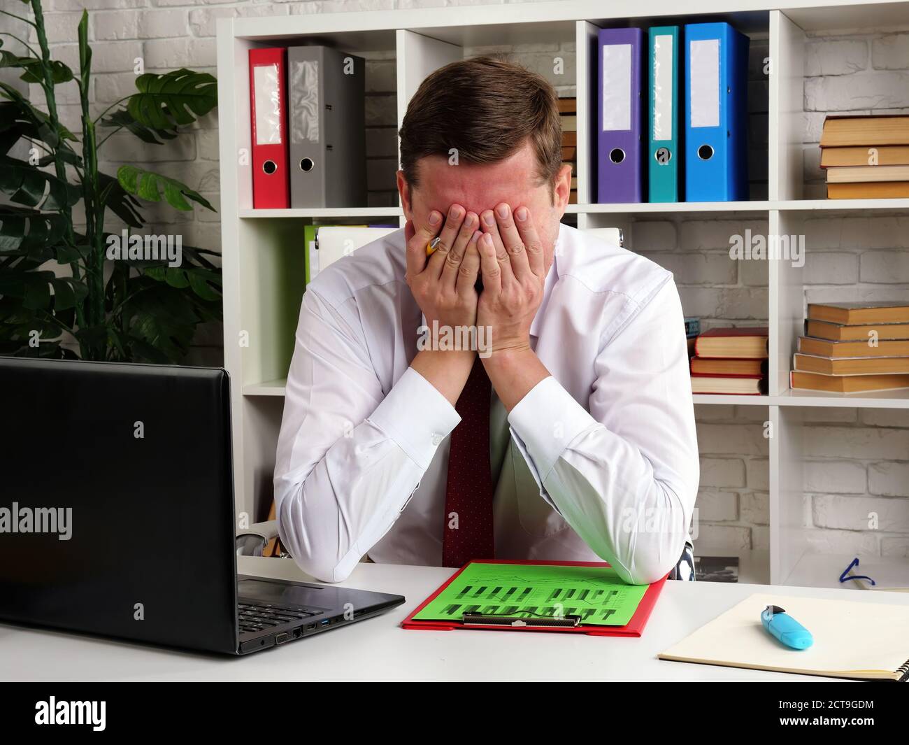 Müde und nachdenklich Geschäftsmann bedeckt sein Gesicht mit den Händen beim Lesen der Audit-Ergebnisse. Stockfoto