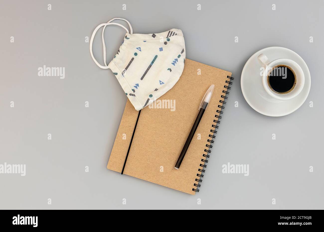 Notizbuch, Maske und Stift auf dem Schreibtisch mit Kaffee. Stockfoto