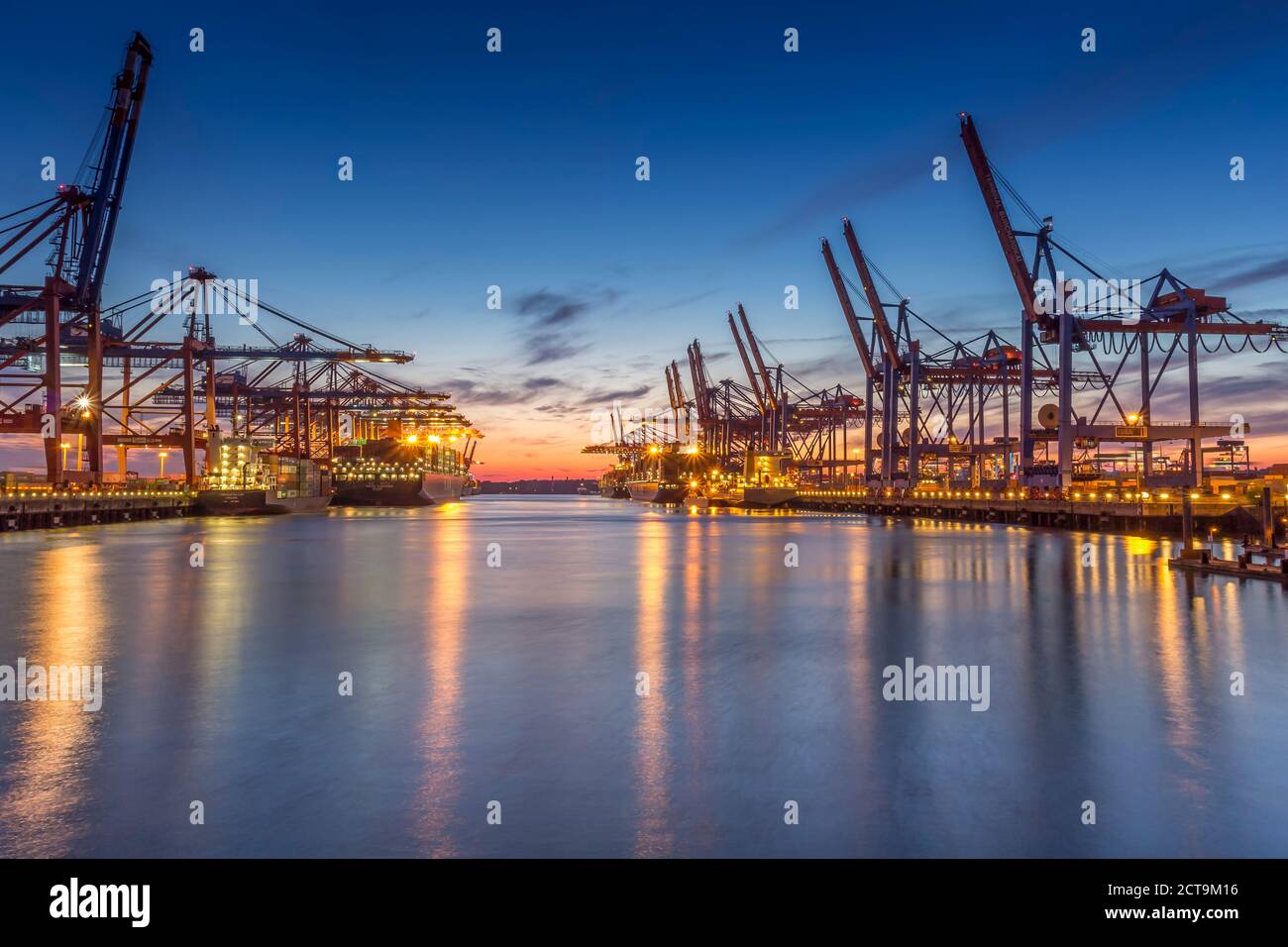 Deutschland, Hamburg, Hamburger Hafen, Containerterminal, Containerkrane und Containerschiffe am Abend Stockfoto