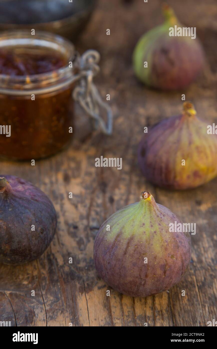 Vier Feigen (Ficus Carica) und ein Glas Feigen Marmelade auf Holztisch, Studio gedreht Stockfoto