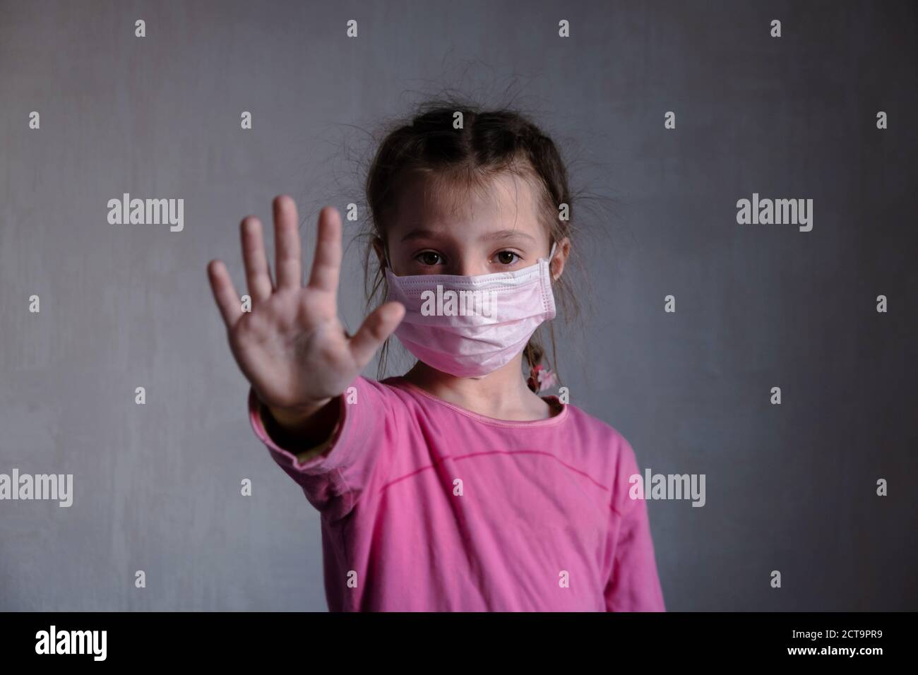 Kleines Mädchen in Maske zeigen Stop Hand. Gesicht in Schutzmaske. Stoppen Sie Coronavirus Stockfoto