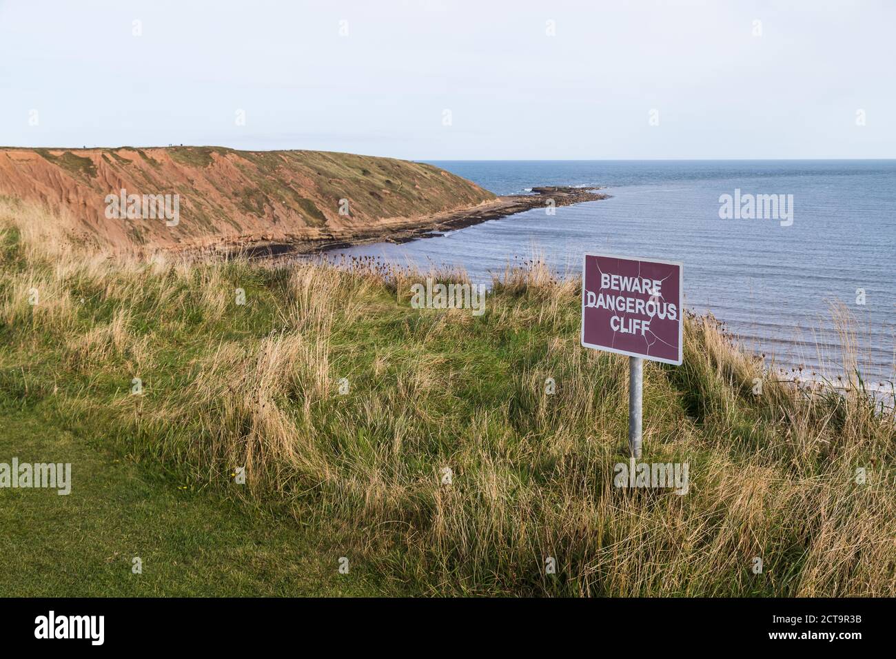 Warnschild an der Anflug auf die zerklüfteten Klippen von Filey Brigg an der Küste von Yorkshire gesehen. Stockfoto