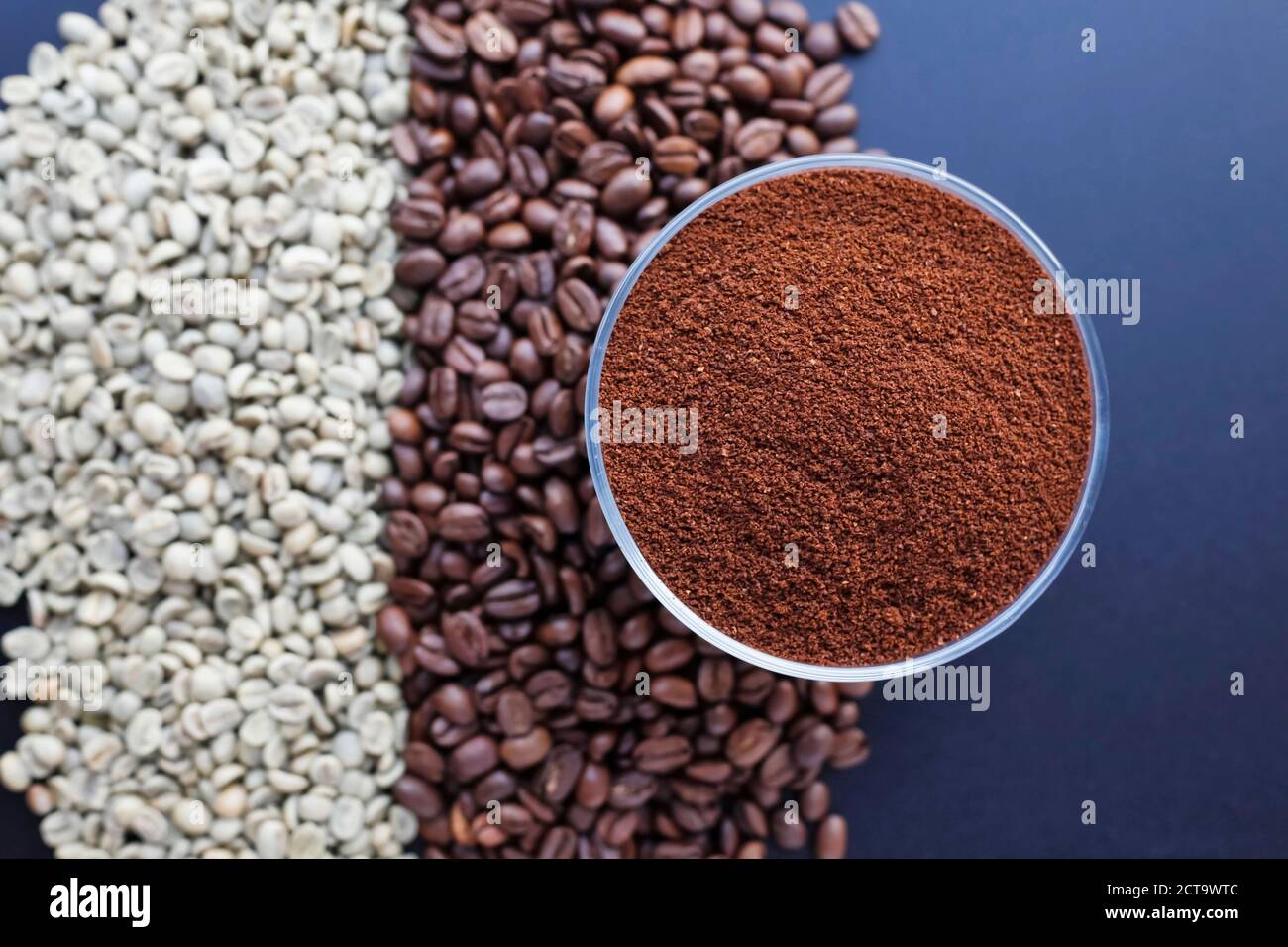 Boden in einer Schale Kaffee und gerösteten und ungerösteten Kaffeebohnen auf einem Tisch Stockfoto