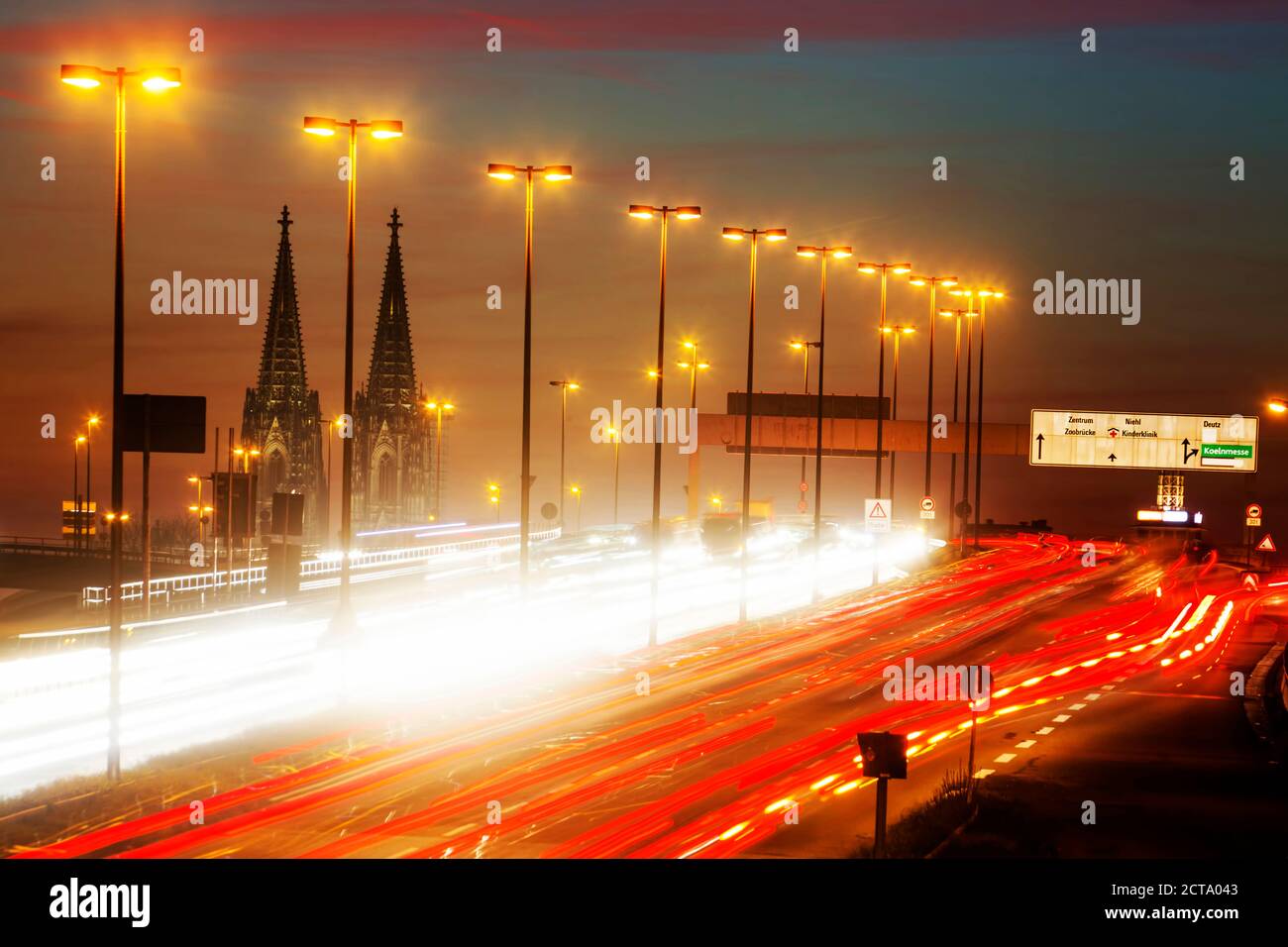Deutschland, Nordrhein-Westfalen, Kölner Dom und Straße Verkehr auf beleuchteten Zoobruecke in der Abenddämmerung Stockfoto