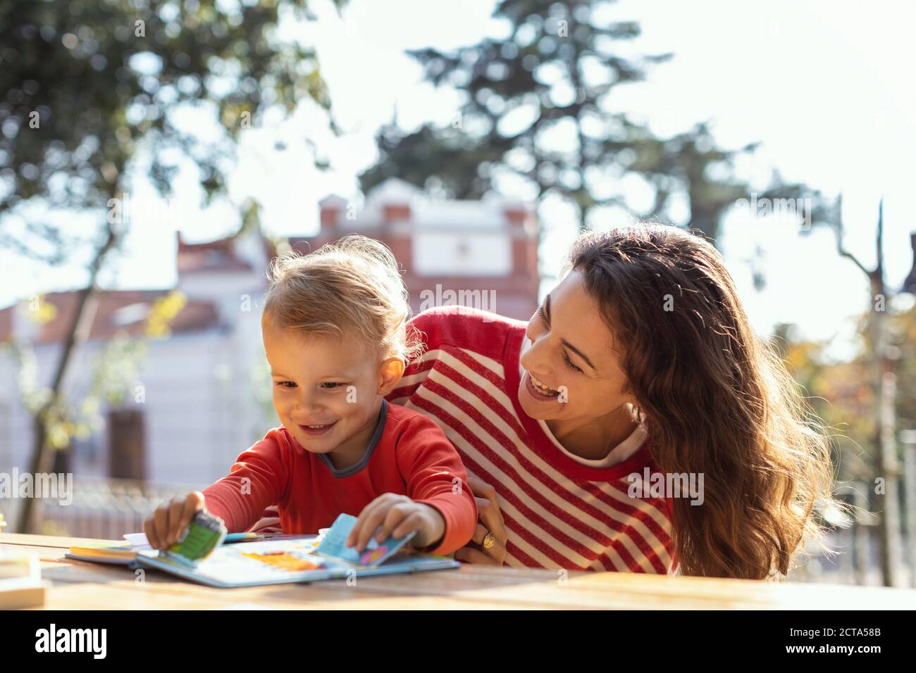 Glückliche Mutter und Kleinkind Lesung Lift-the-Flap Kinderbuch in der Garten Stockfoto Glückliche Mutter und Kleinkind Lesung Lift-the-Flap Kinderbuch in der Garten Stockfoto