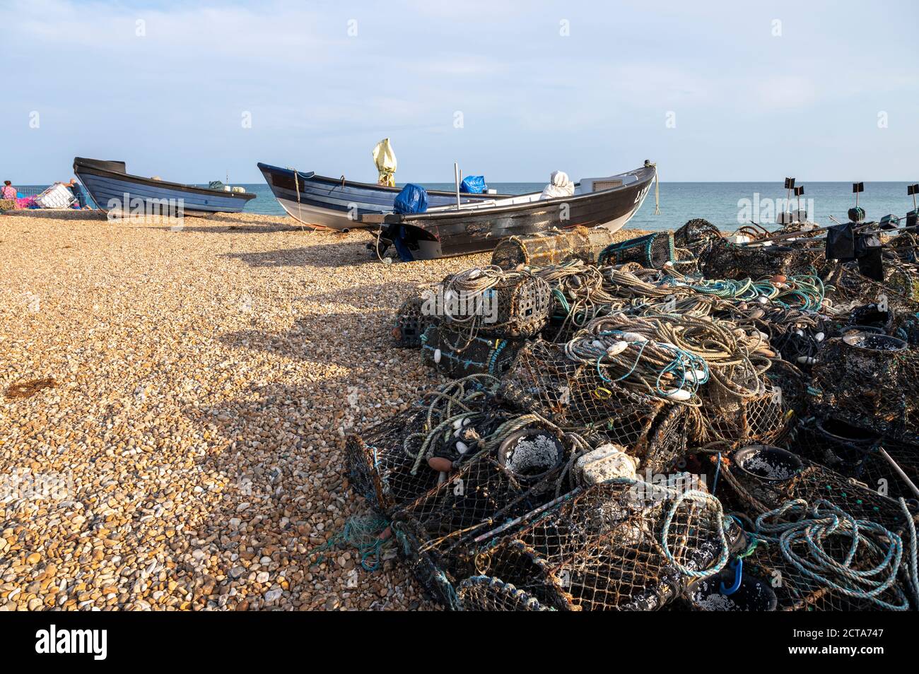 Lokale Fischerboote am Strand umgeben von Angelausrüstung, Hummertöpfen, Netzen und Seil. Stockfoto