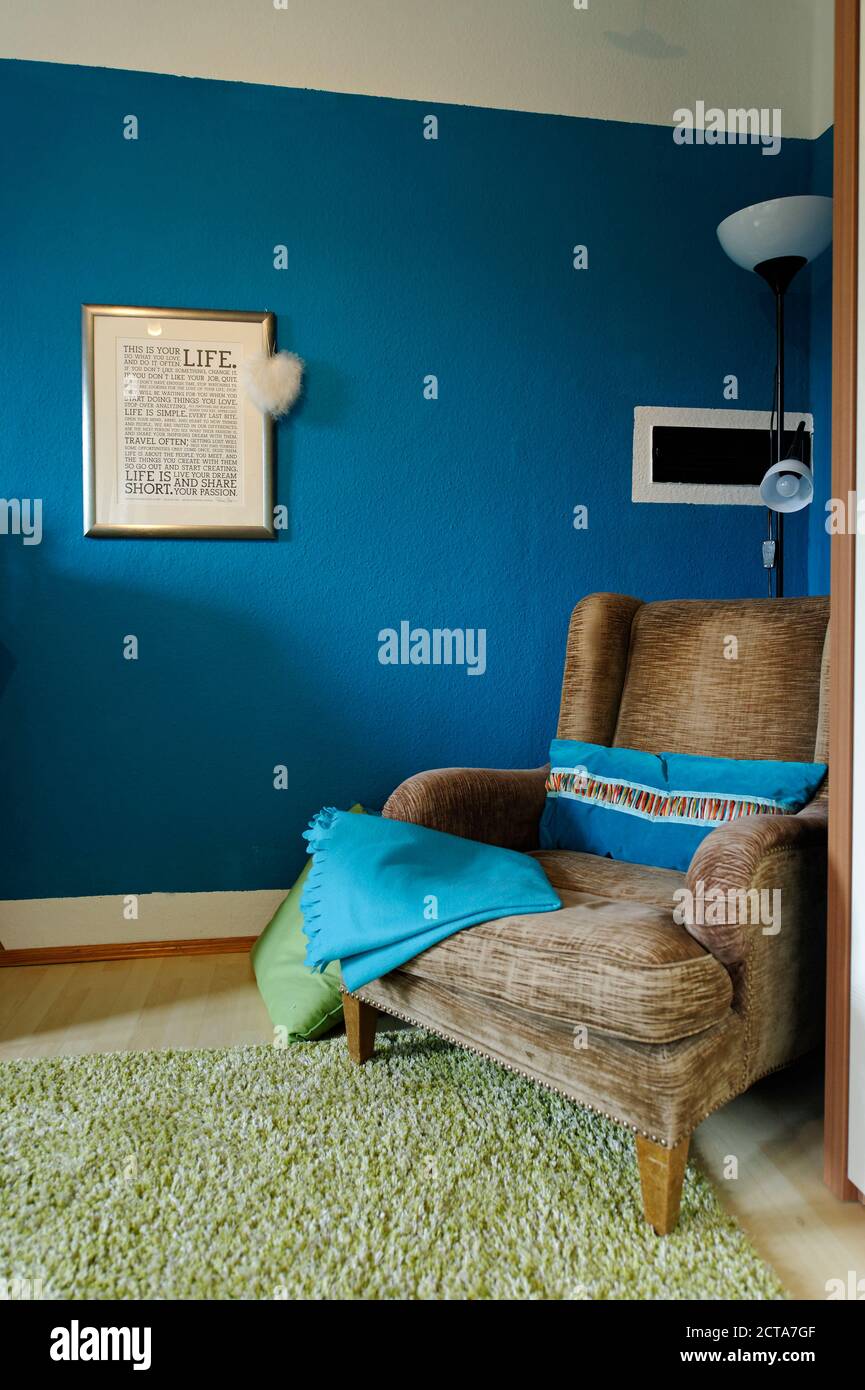Ohrensessel stehen in einer Ecke des Wohnzimmers vor blaue farbige Wand Stockfoto