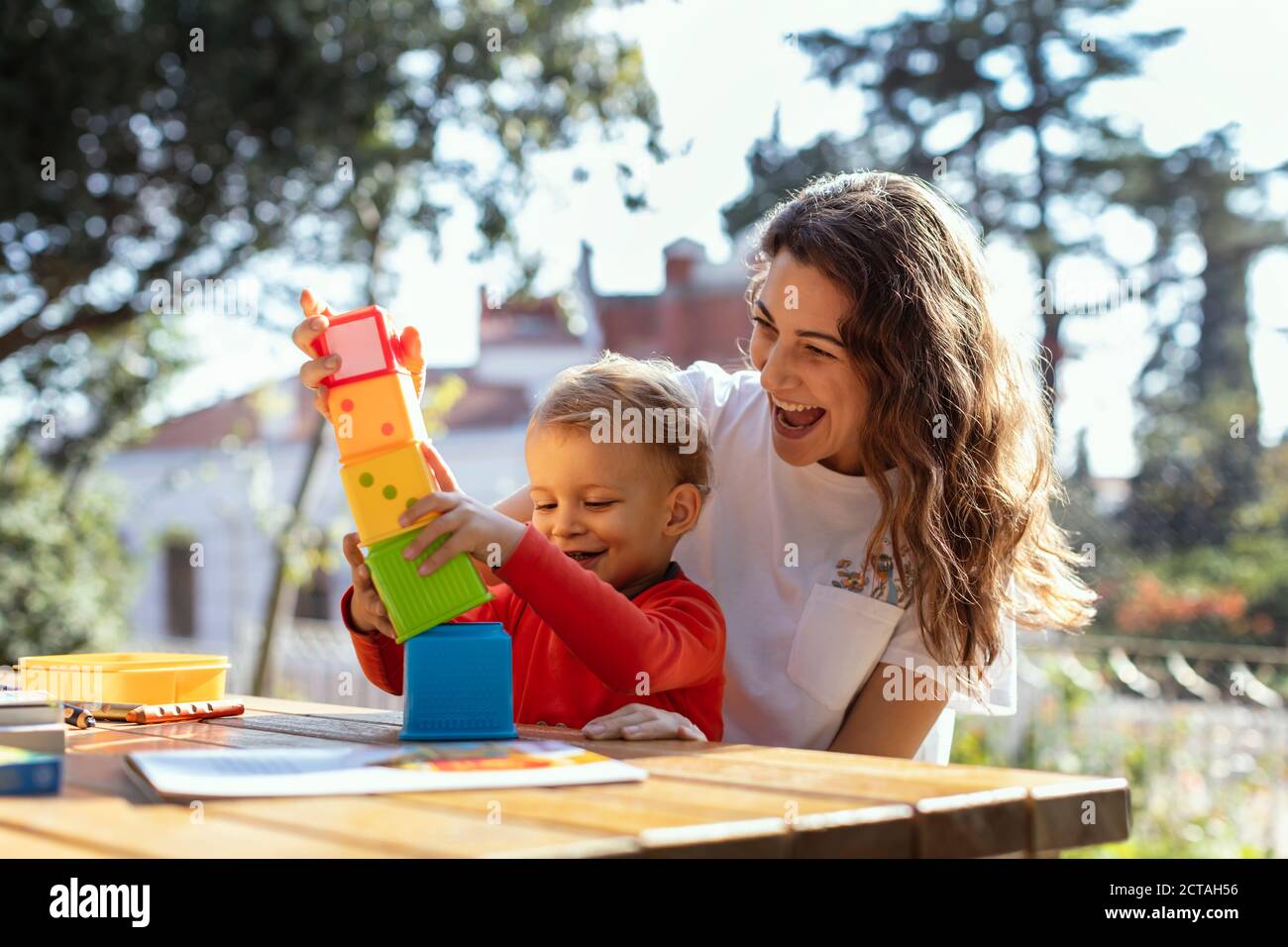 Junge Frau und Sohn spielen pädagogische Würfel Spielzeug im Garten Stockfoto