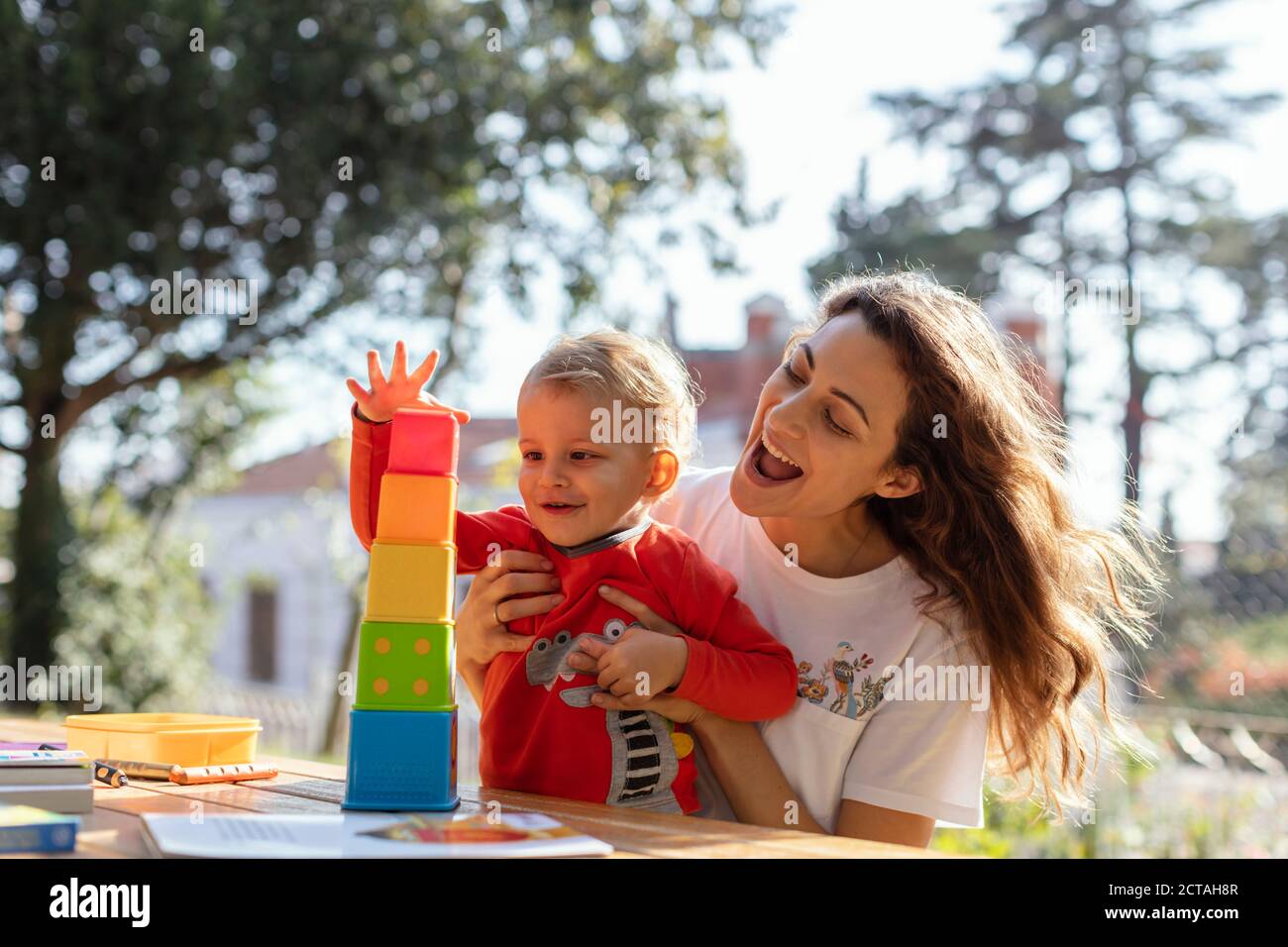 Junge Frau und Sohn spielen pädagogische Würfel Spielzeug im Garten Stockfoto