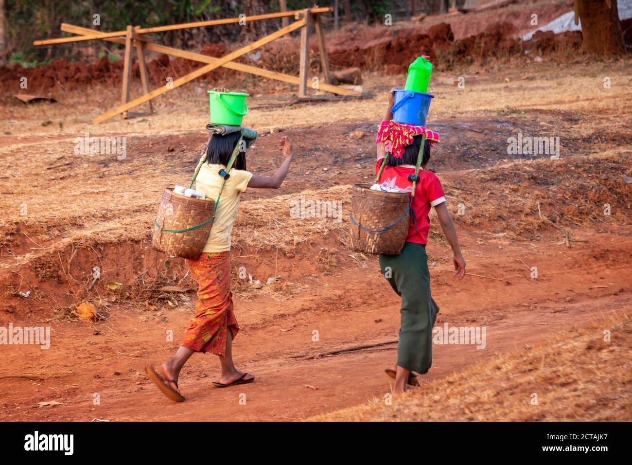 Zwei Mädchen holen Wasser mit Plastikeimer und Dosen in Burma, Myanmar Stockfoto