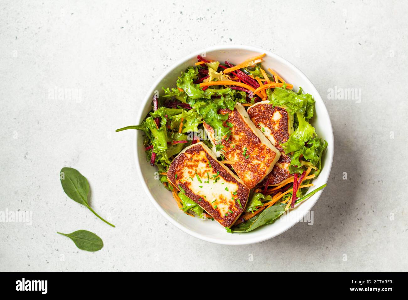 Grüner Salat mit gegrilltem Halloumi-Käse, Rüben und Karotten in einer weißen Schüssel. Diät-Food-Konzept. Stockfoto