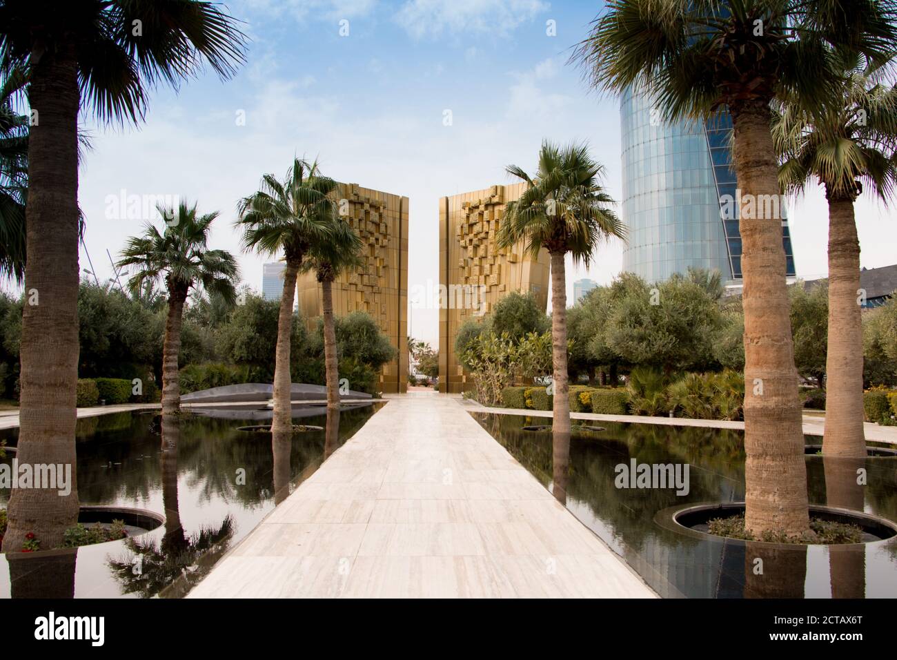 Das goldene Denkmal zur Feier des Jubiläums der Kuwait-Verfassung mit Palmen und Brunnen vor. Al Shaheed Park, Kuwait. Stockfoto