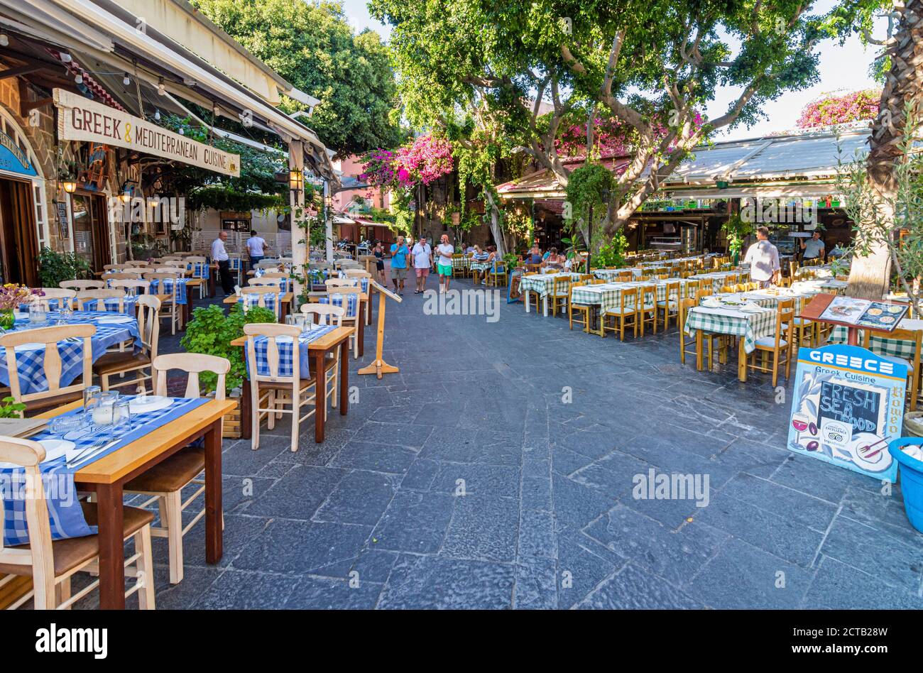 Tische und Stühle der griechischen Taverne säumen den Fußweg in der Altstadt von Rhodos, Dodekanes, Griechenland Stockfoto