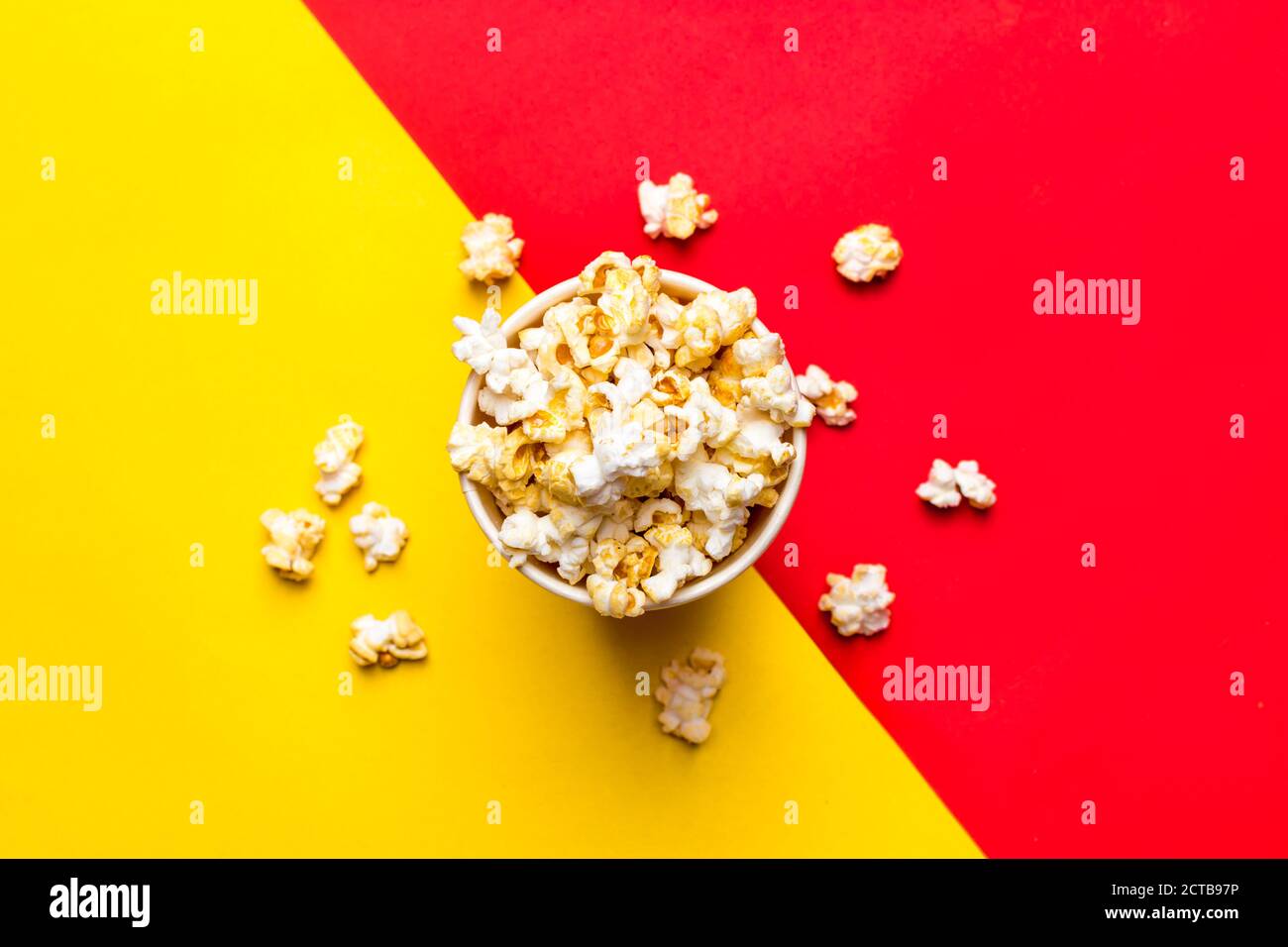 Popcorn in rot-weißem Karton auf rot und Gelber Hintergrund Draufsicht Flat Lay Copy Space Stockfoto