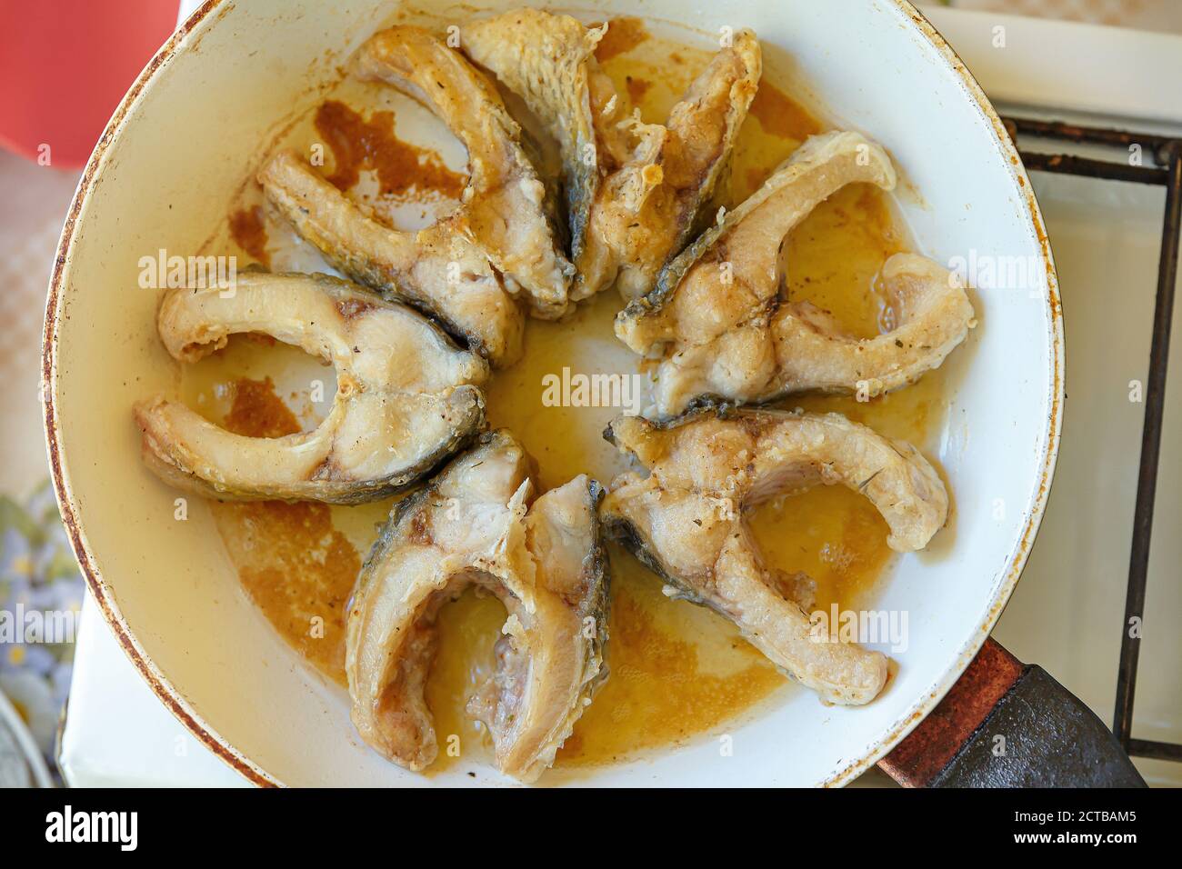 Fischstücke werden in einer weißen Pfanne gebraten. Frittierte Karpfenstücke. Kochen zu Hause. Stockfoto