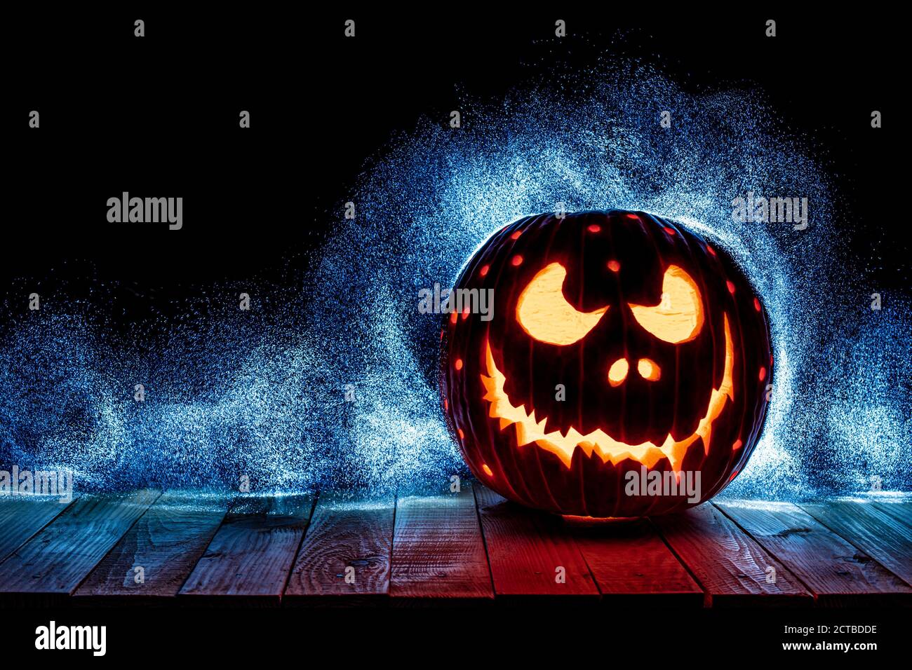 halloween Kürbis geschnitzt auf Holzplanken, dunkler Hintergrund mit blauen Lichtern Stockfoto