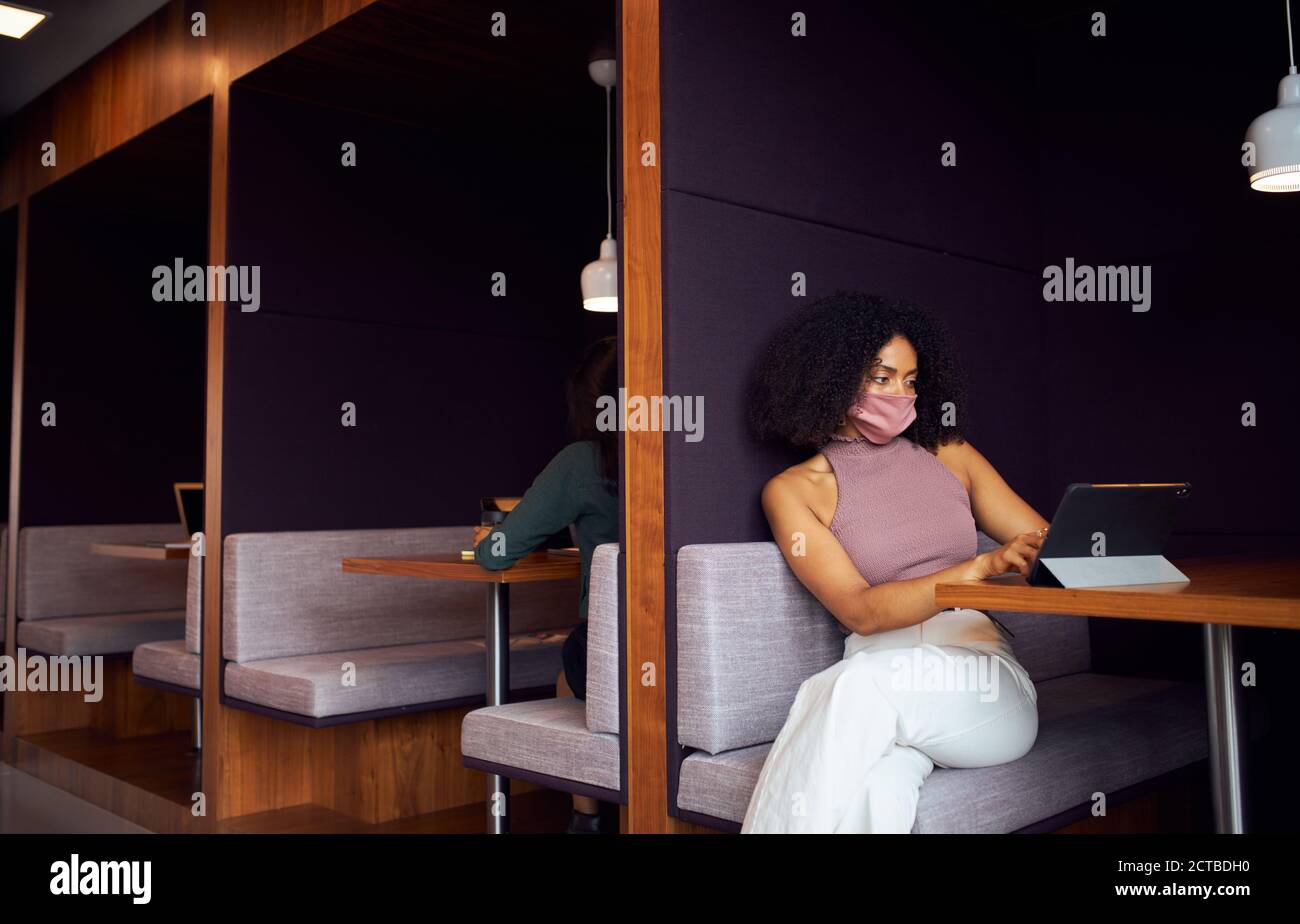 Geschäftsfrau Trägt Maske Arbeitet In Sozial Distanzierten Kabine Im Büro Während Der Gesundheitsinpandemie Stockfoto