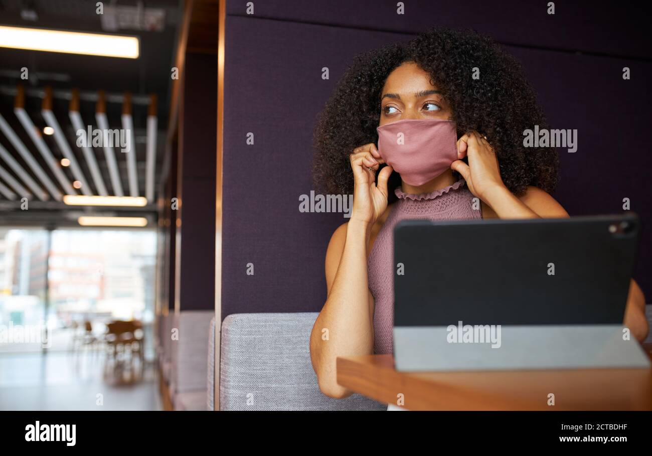 Geschäftsfrau Trägt Maske Arbeitet In Sozial Distanzierten Kabine Im Büro Während Der Gesundheitsinpandemie Stockfoto
