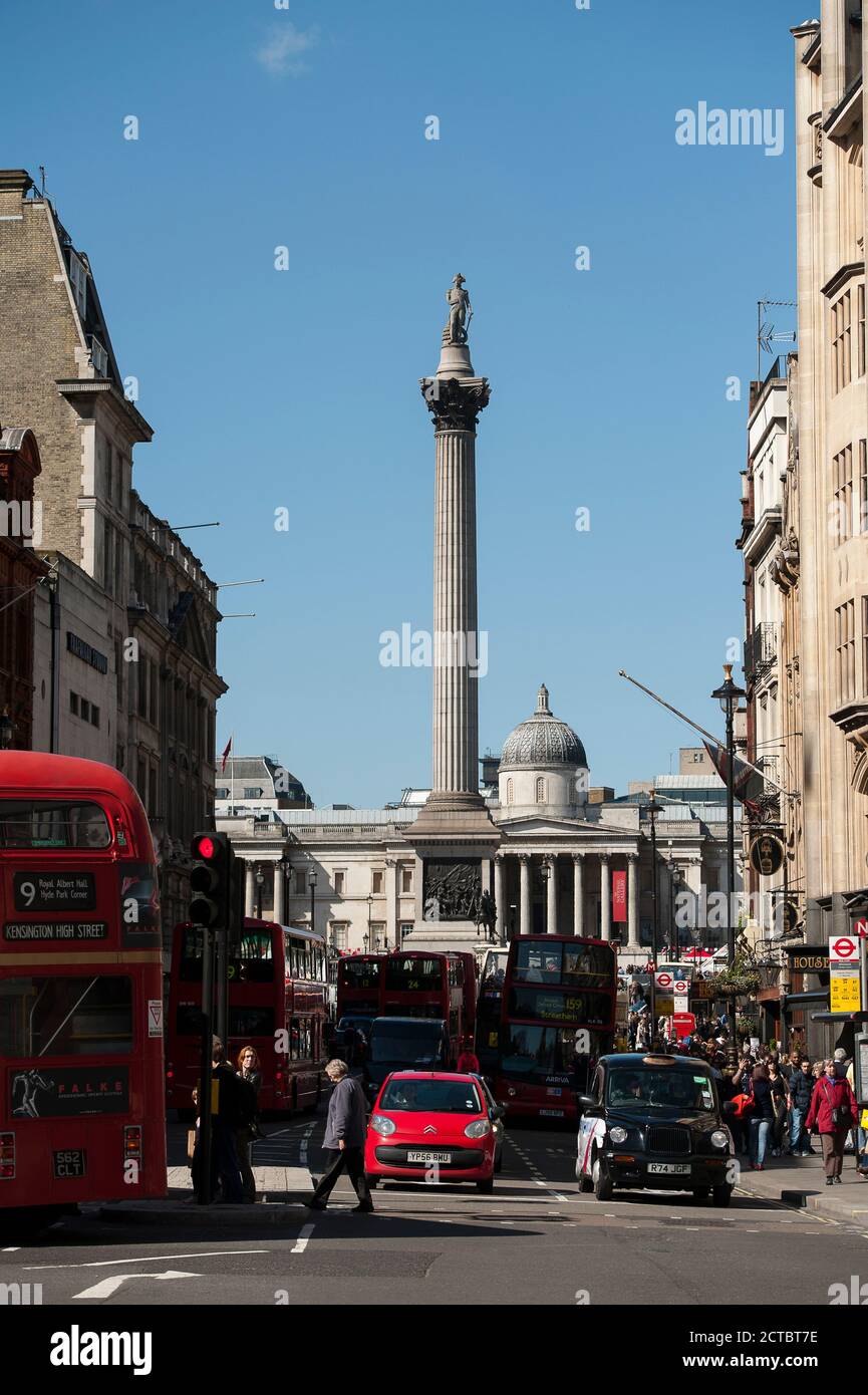 Verkehr auf einer belebten Straße im Zentrum von London mit Nelson's Column im Trafalgar Square im Hintergrund, England. Stockfoto