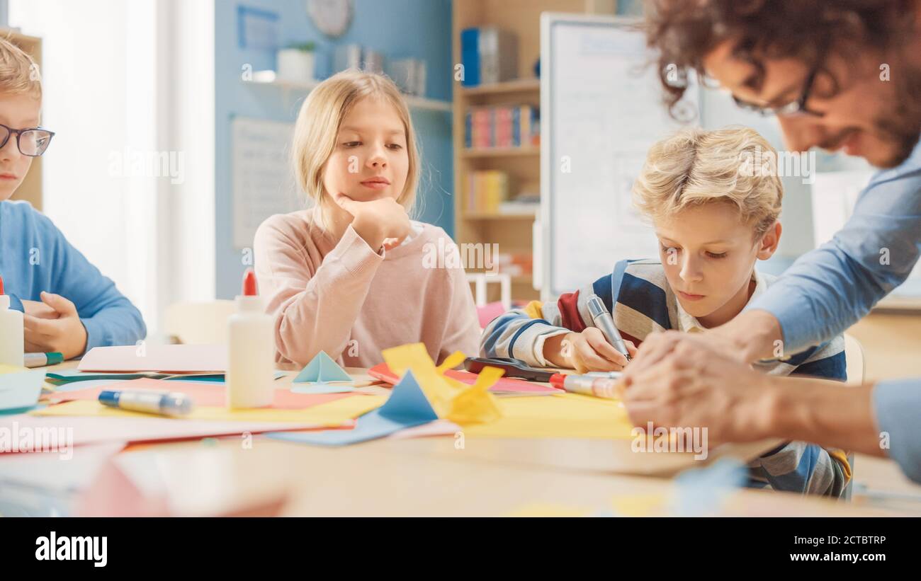 Grundschule Kunst Handwerk Klasse: Begeisterter Lehrer, verschiedene Gruppe von intelligenten Kindern Spaß haben zusammen auf Handwerk Projekt, mit bunten Stockfoto