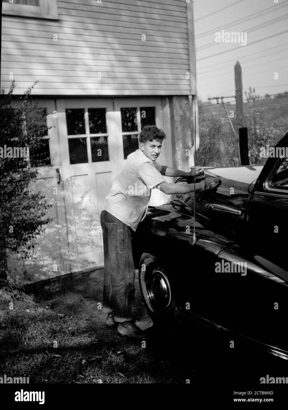 Teenager, der die Haube eines Familienwagens poliert, 1930er Jahre, USA Stockfoto