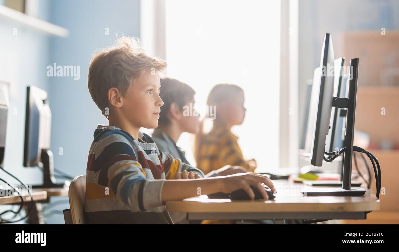 Grundschule Informatik Klassenzimmer: Smart Little Schoolboy arbeitet auf Personal Computers, Lernen Programmiersprache für Software-Codierung Stockfoto