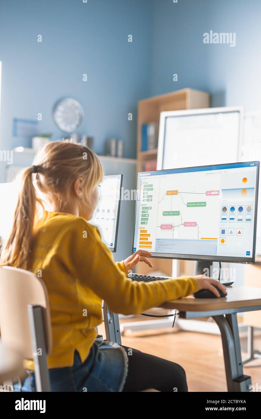 Grundschule Informatik Klassenzimmer: Nettes kleines Mädchen verwendet Computer, Programmiersprache für Software-Codierung zu lernen. Schulkinder Stockfoto