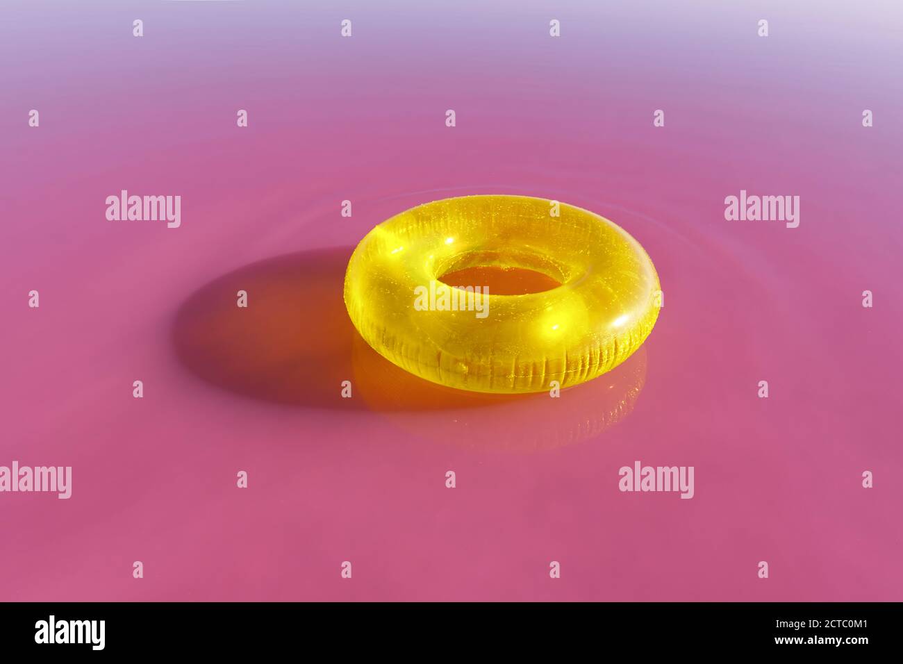 Leuchtend gelbe aufblasbare Ring schweben in rosa Wasser See. Kreativer Farbhintergrund Stockfoto
