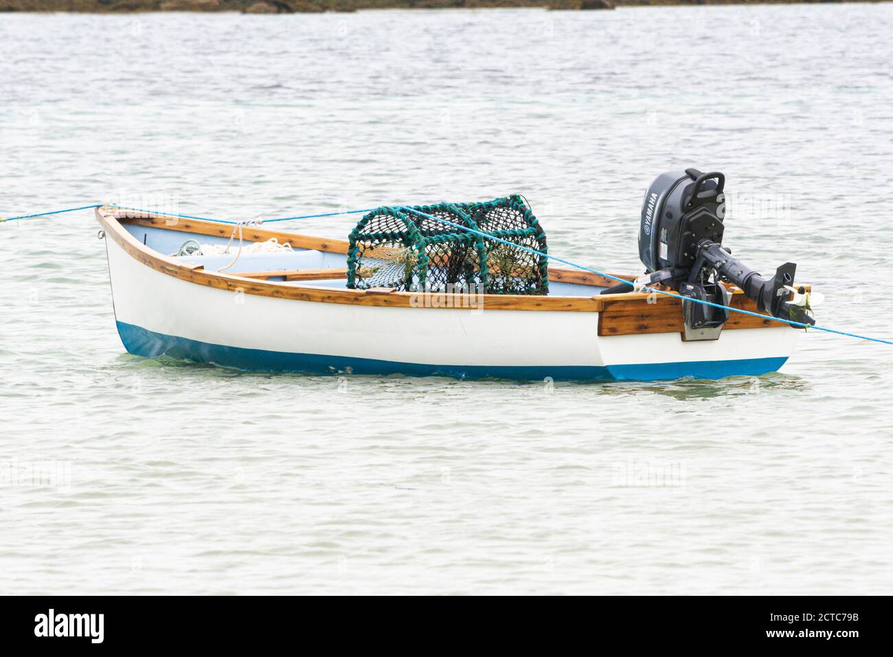 Ein Hummertopf in einem kleinen Holzboot vor Anker von Green Porth, Tresco, Isles of Scilly Stockfoto