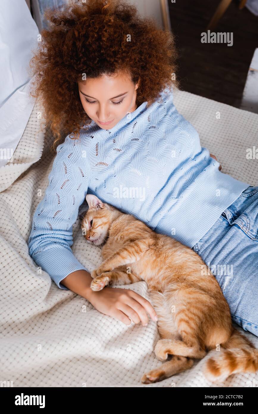 High-Angle-Ansicht der rothaarigen Frau in der Nähe von Ingwer liegen Katze auf dem Bett Stockfoto