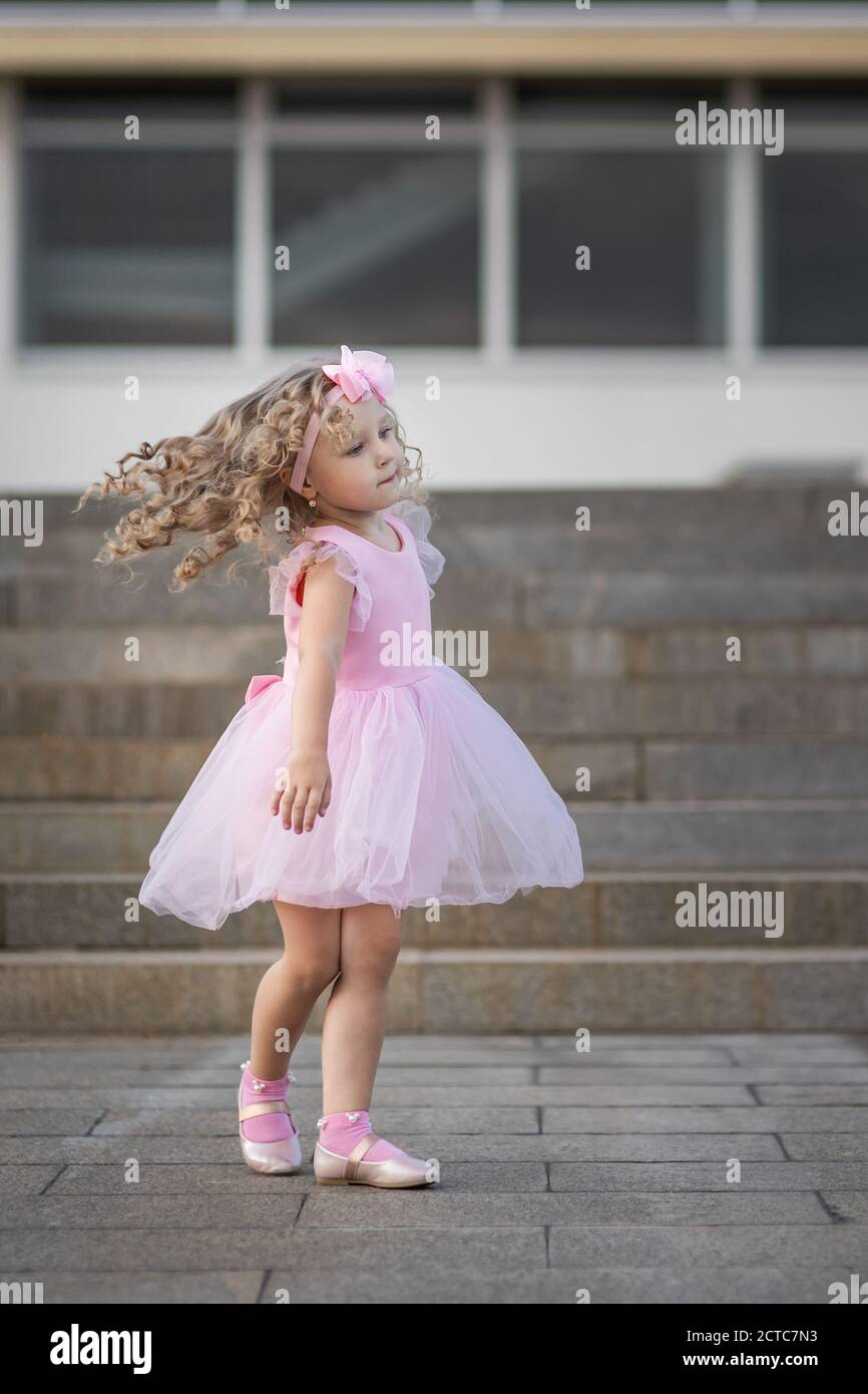 Kleines Mädchen in rosa Kleid Spinnen herum auf der Straße Stockfotografie  - Alamy