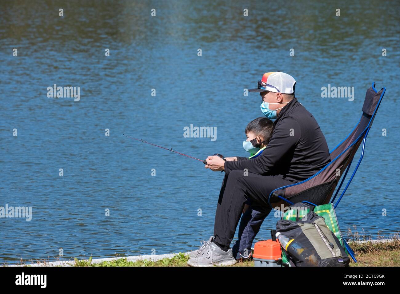 Ein asiatischer amerikanischer Vater und Sohn fischen gemeinsam am See in einem Park in Queens, New York City. Stockfoto