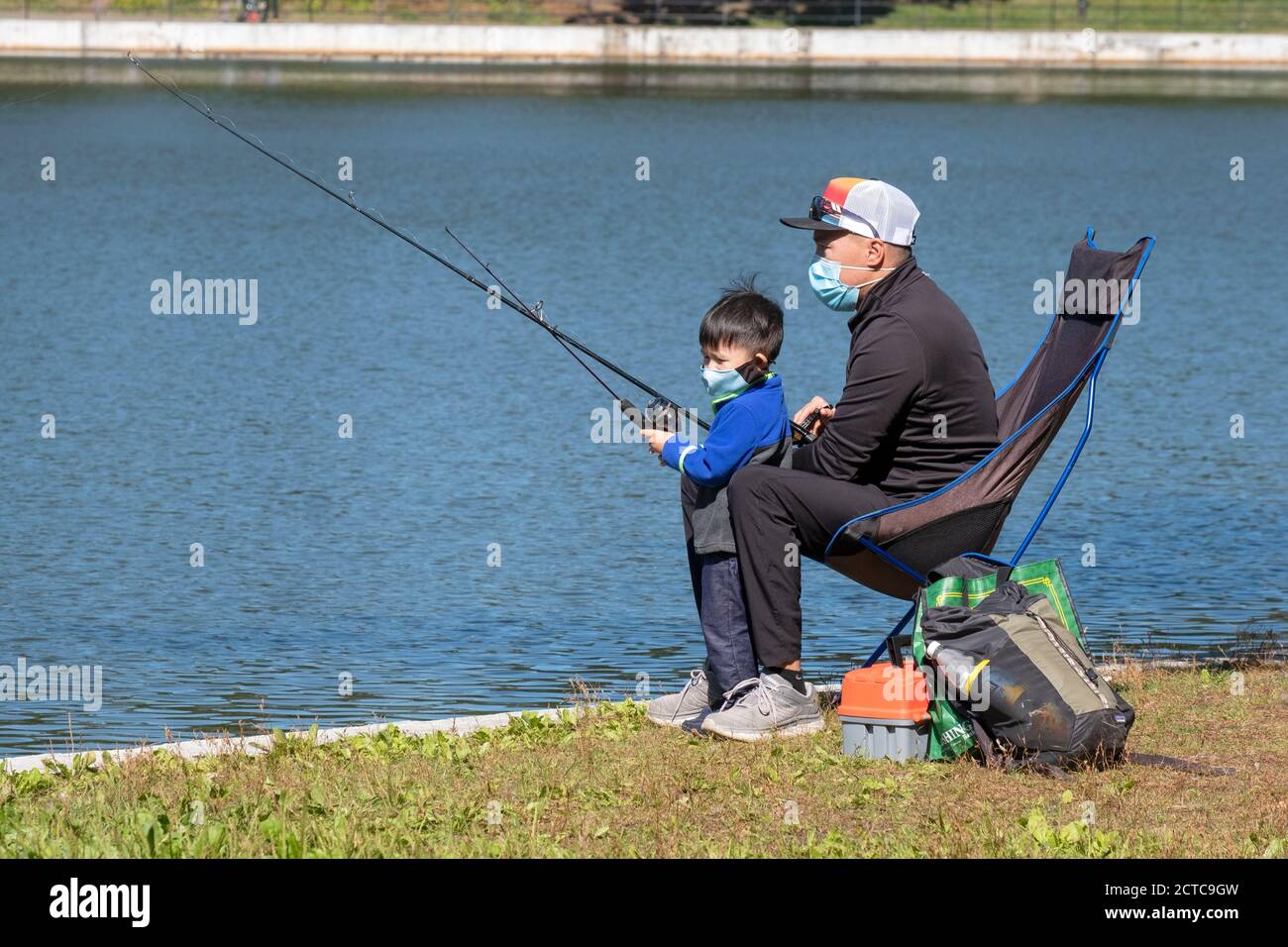 Ein asiatischer amerikanischer Vater und Sohn fischen zusammen an einem See in einem Park in Queens, New York City. Stockfoto