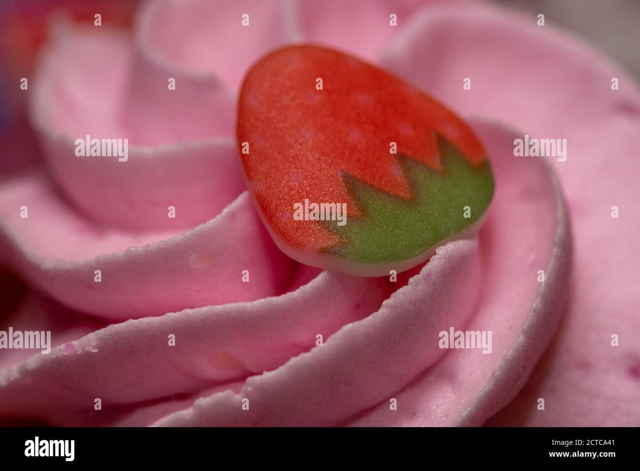 Eine Nahaufnahme der Vereisung und Dekoration eines Erdbeere Cupcake mit selektivem Fokus Stockfoto