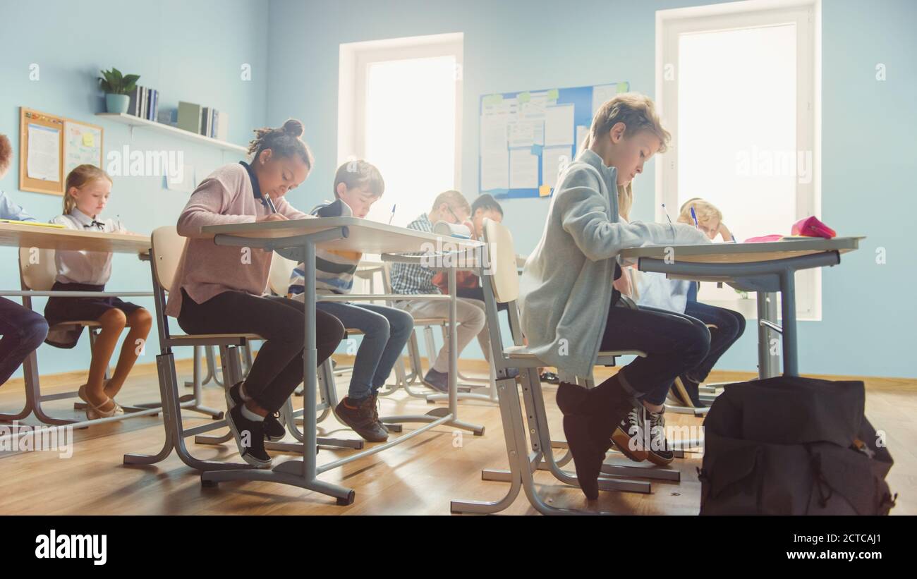 Aufnahme eines Klassenzimmers voller Kinder. In der Grundschule Gruppe der Smart multiethnischen Kinder Schreiben in Übung Notebooks und Lernen. Niedrig Stockfoto