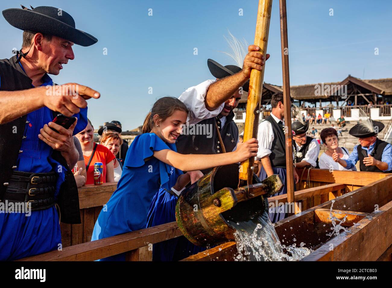 Shepherd hilft ihrer Tochter, Wasser aus dem zu ziehen Traditioneller Brunnen im ländlichen Ungarn Stockfoto