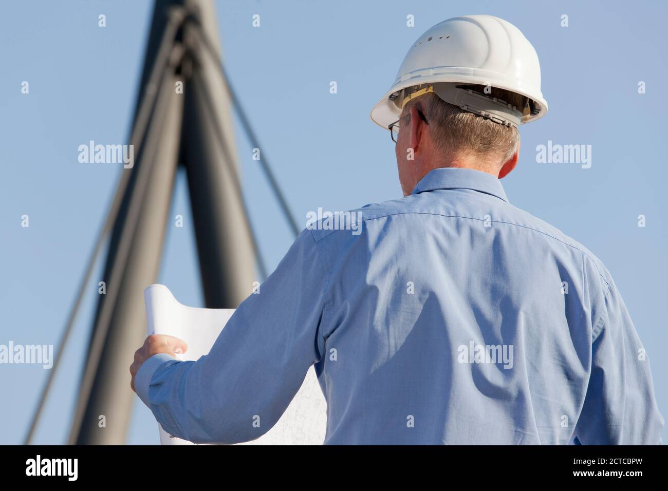 Architekt oder Ingenieur beim Lesen eines Bauplans vor Industrieller Hintergrund - Fokus auf den Kopf Stockfoto