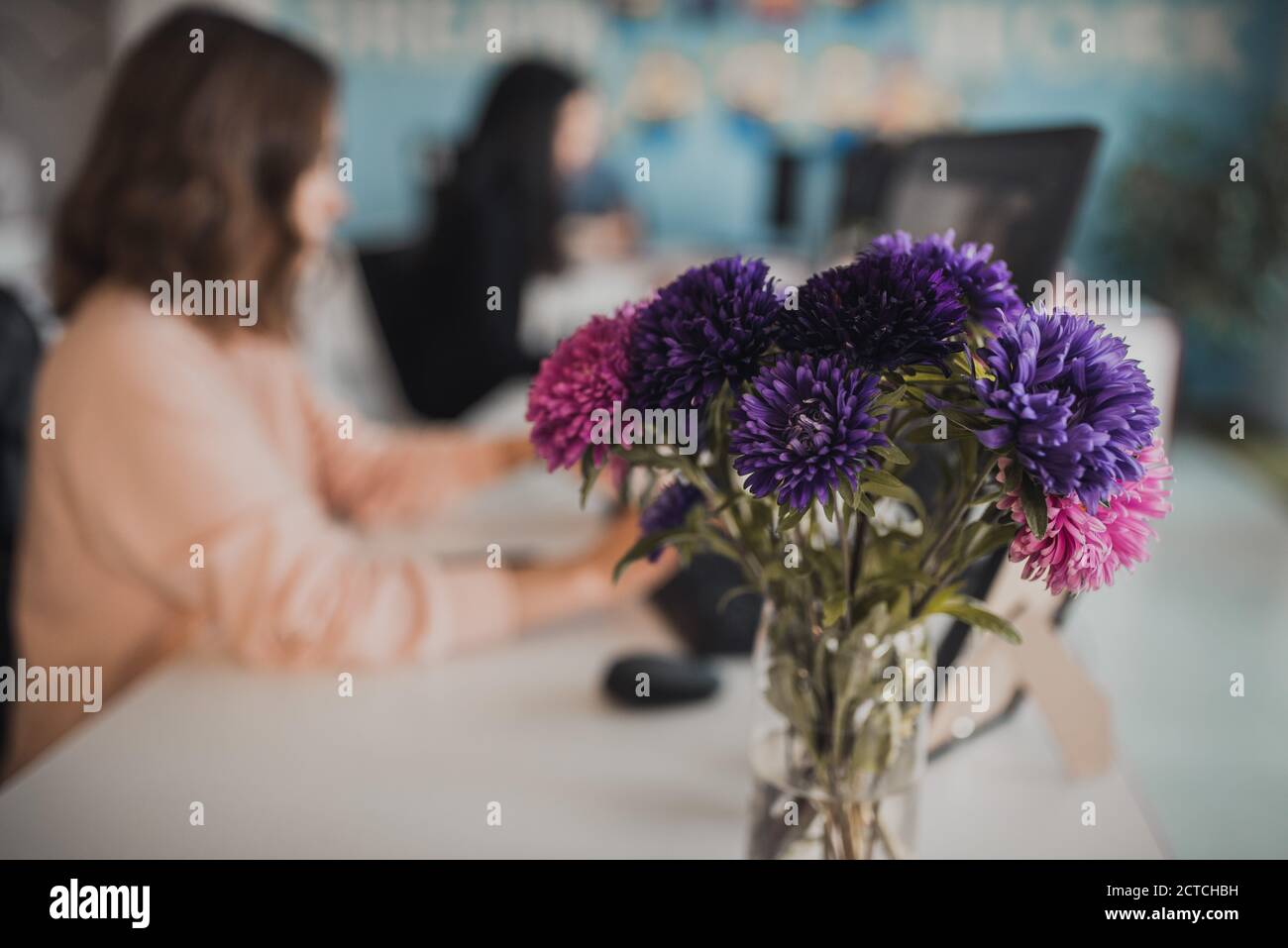Ein Bouquet von bunten Blumen auf dem Hintergrund eines Frau, die am Computer arbeitet Stockfoto