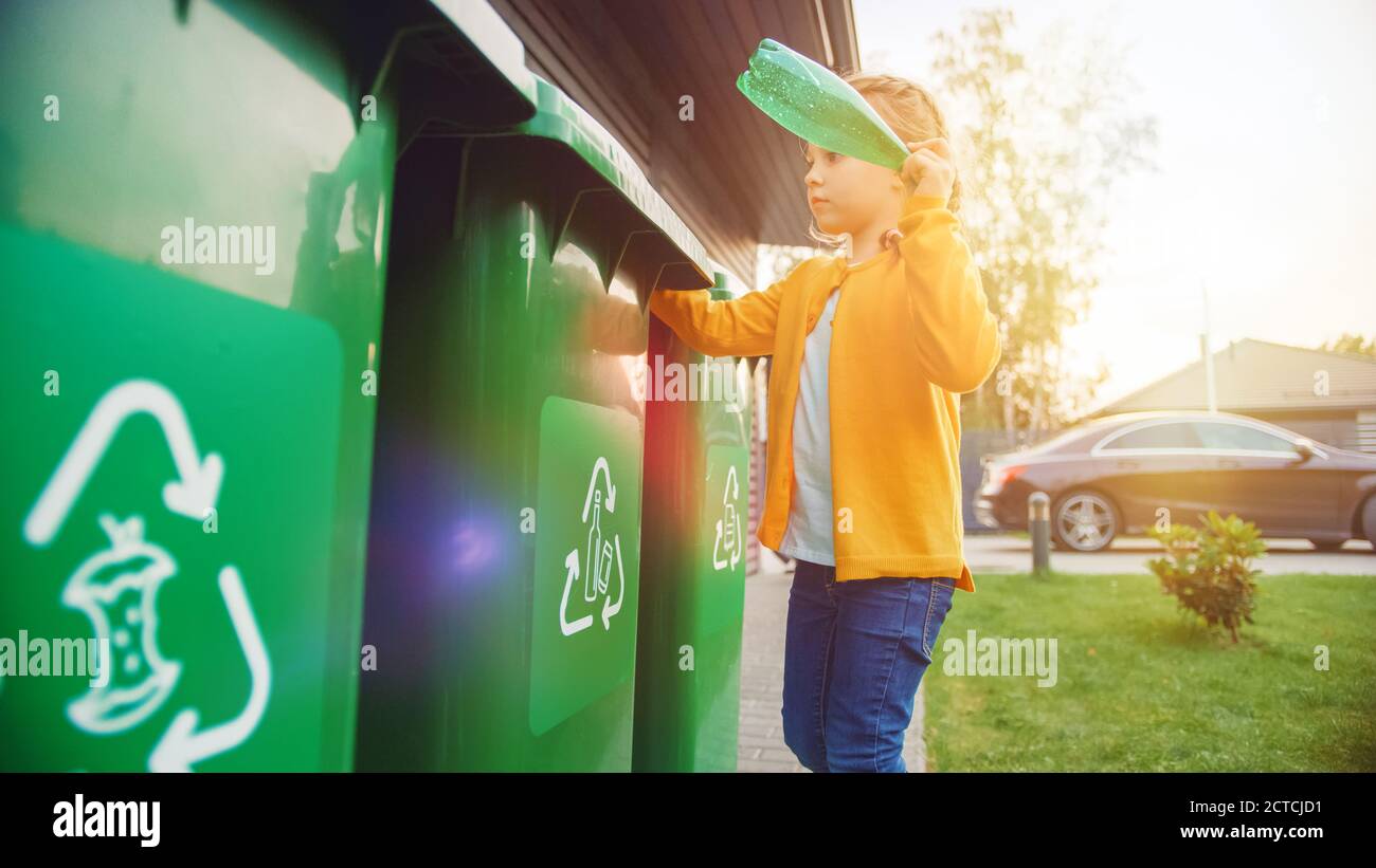 Junges Mädchen wirft weg eine leere Plastikflasche in einen Papierkorb. Sie verwendet richtigen Garbge bin, weil diese Familie Abfall sortiert und hilft Stockfoto