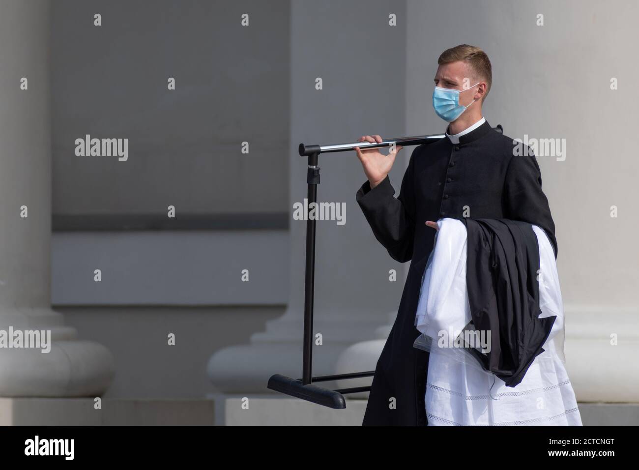 Junger Priester mit Schutzmaske, der zur Kirche geht Zur Feier der Messe während der zweiten Welle des Covid- oder Coronavirus Ausbruch Stockfoto