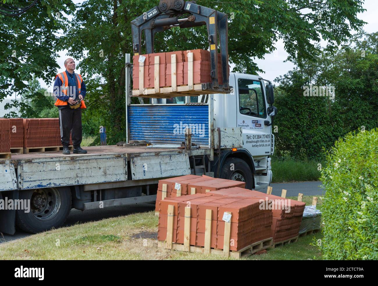 BUCKINGHAM, Großbritannien - 09. Juni 2020. Mann, der Baustoffe (Dachziegel) liefert, Lieferwagen mit Kran, Großbritannien Stockfoto