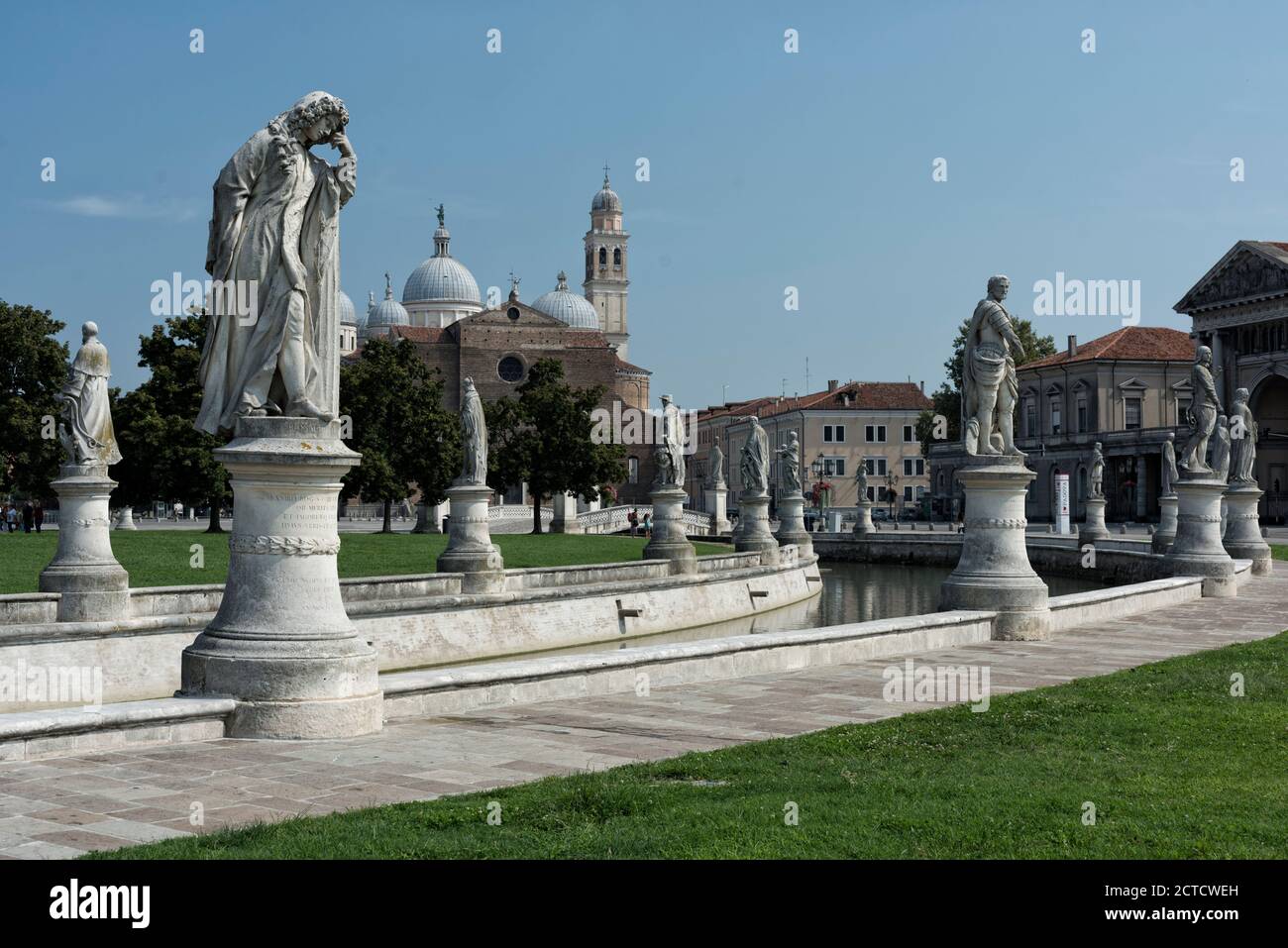 Prato della Valle, sein Kanal und viele beeindruckende klassische Statuen auf ihren Sockeln. Die Basilika Santa Giustina im Hintergrund, Padua, Venetien, Italien. Stockfoto