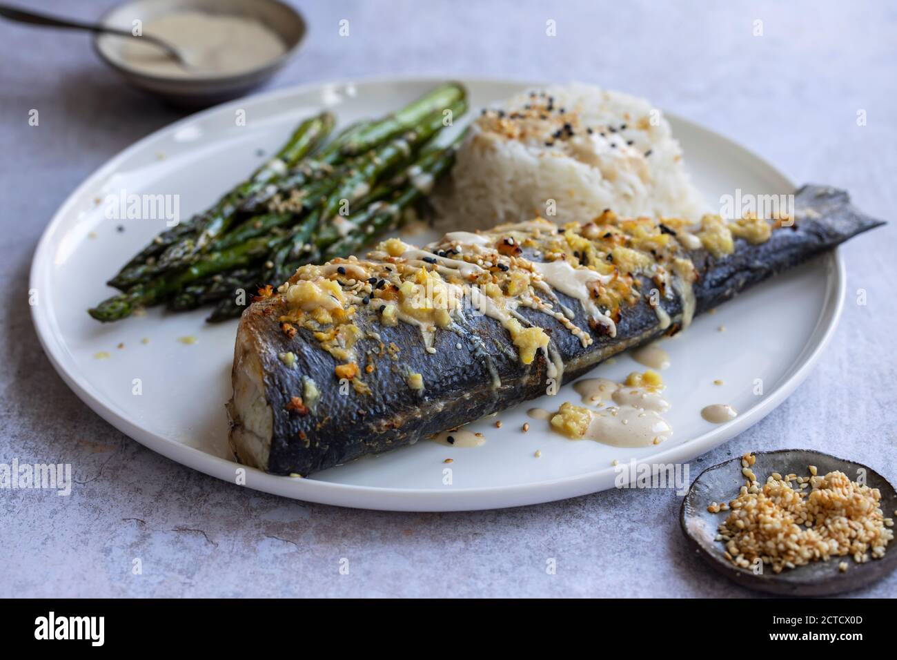 Gebackener Seebarsch mit Zitronengras, Ingwer, Tahini-Sauce und Sesamsamen Stockfoto