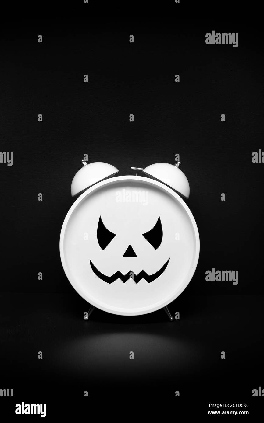 Retro-Uhr mit gruseligen Gesicht auf dunklem Hintergrund. Halloween oder Angst Zeit Konzept. Speicherplatz kopieren Stockfoto