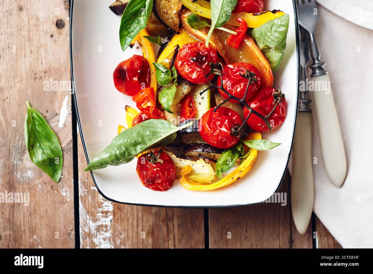 Salat mit gerösteten Tomaten, Auberginen, Zucchini, Paprika und grünem Basilikum. Stockfoto