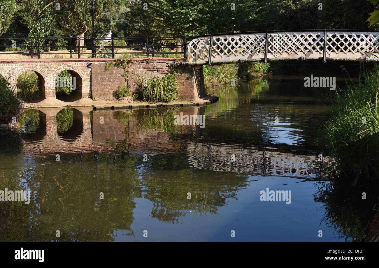 Eine Fußgängerbrücke spiegelte sich in den stillen Gewässern des Wey In Guildford Stockfoto